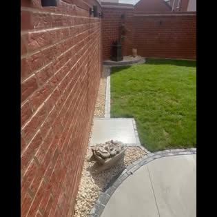 Paving detail alongside a garden lawn and wall