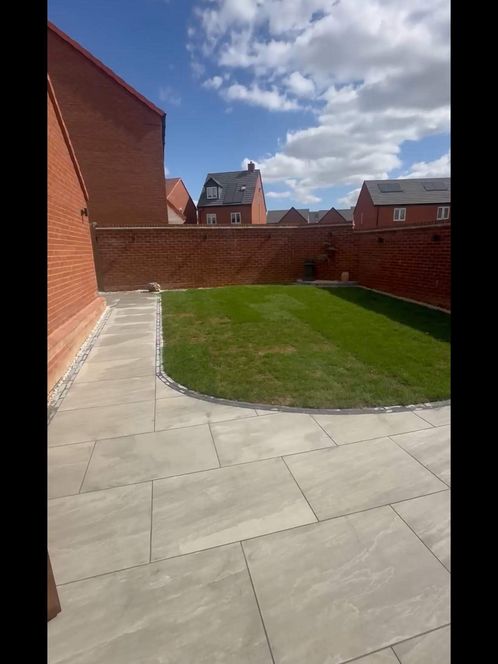 Completed paved patio wrapping around a lawn